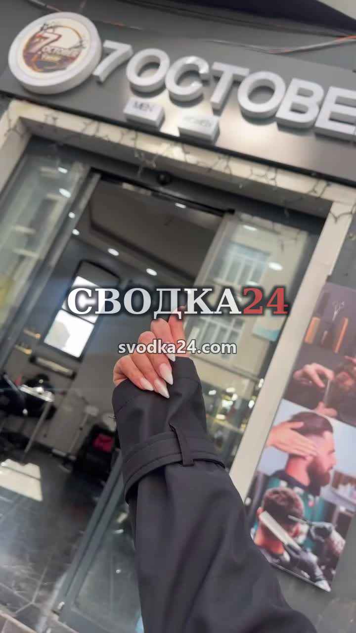 Полный кадр вывески 7 OCTOBER: рука указывает на вход парикмахерской